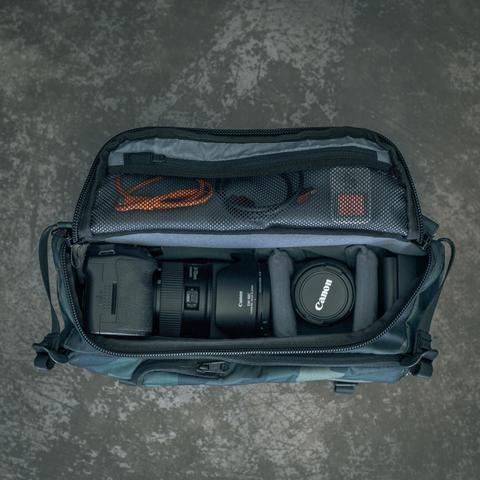 HEX Ranger Camo DSLR Sling, top view, unzipped to show an assortment of camera gear inside
