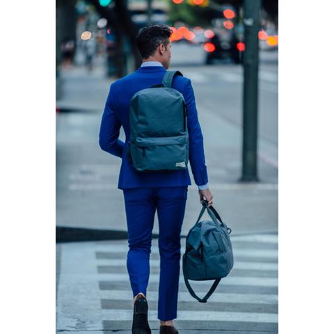 Man carrying HEX Aspect Exile Solid Grey Backpack across the street