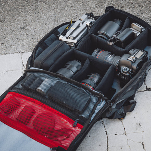 Close up view of the main compartment open with multiple lenses and a DSLR camera in the backpack
