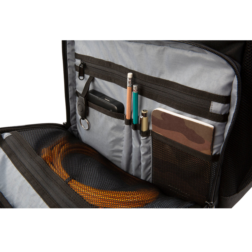 Close up view of one of the accessory pockets zipped open showing storage for a notebook, pencils, phone, and cords on the Hex Black Cinema Backpack