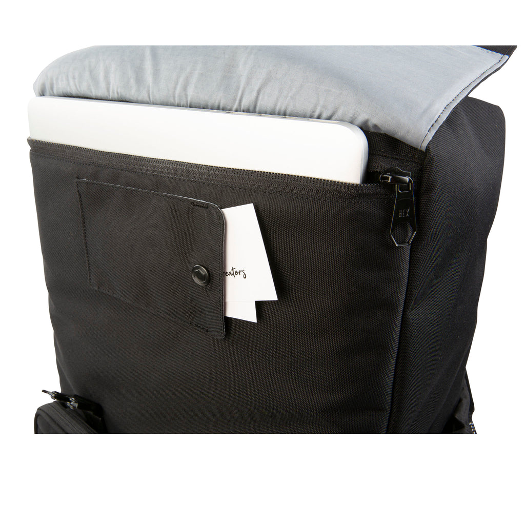 Close up view of the laptop sleeve folded open with a laptop stored on the Hex Black Cinema Backpack