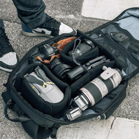 HEX Ranger Clamshell Black DSLR Backpack, front view, unzipped to show assortment of camera gear stored inside